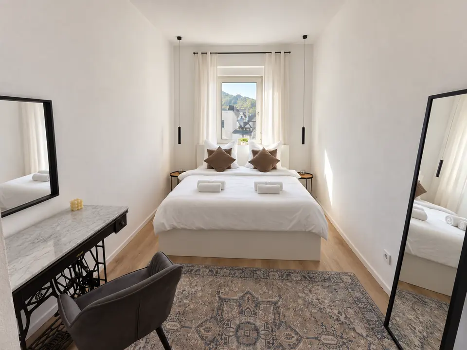 Das helle Schlafzimmer im Marktplatz Apartment mit Doppelbett, weichen Kissen und warmen Nachttischleuchten