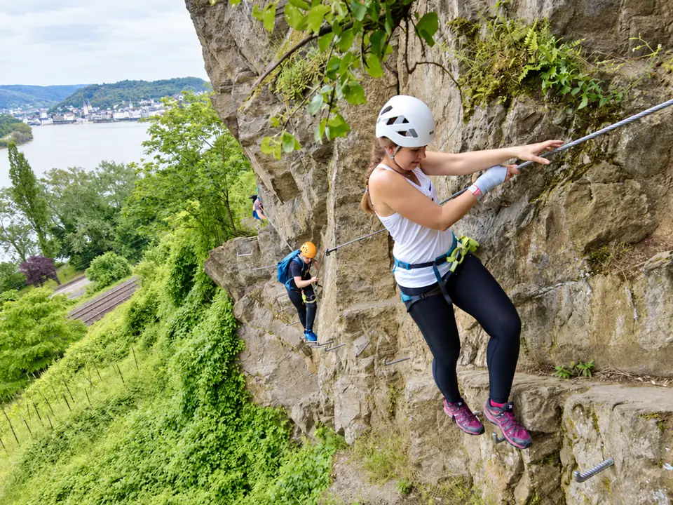 Kletterer mit Helm und Sicherung am Felsen über dem Rhein