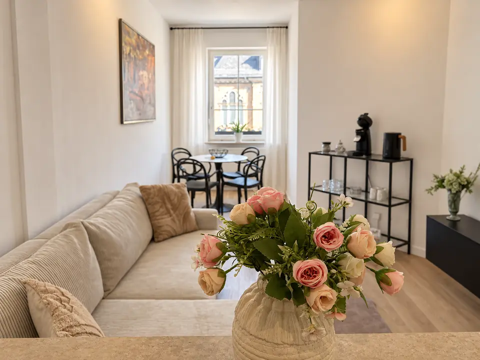 Blumen im Vordergrund und heller Wohnbereich mit Sofa