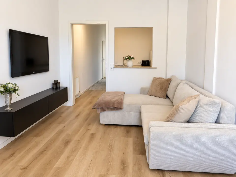 Sofabereich mit Kissen und Decke, gegenüber dem Fernseher